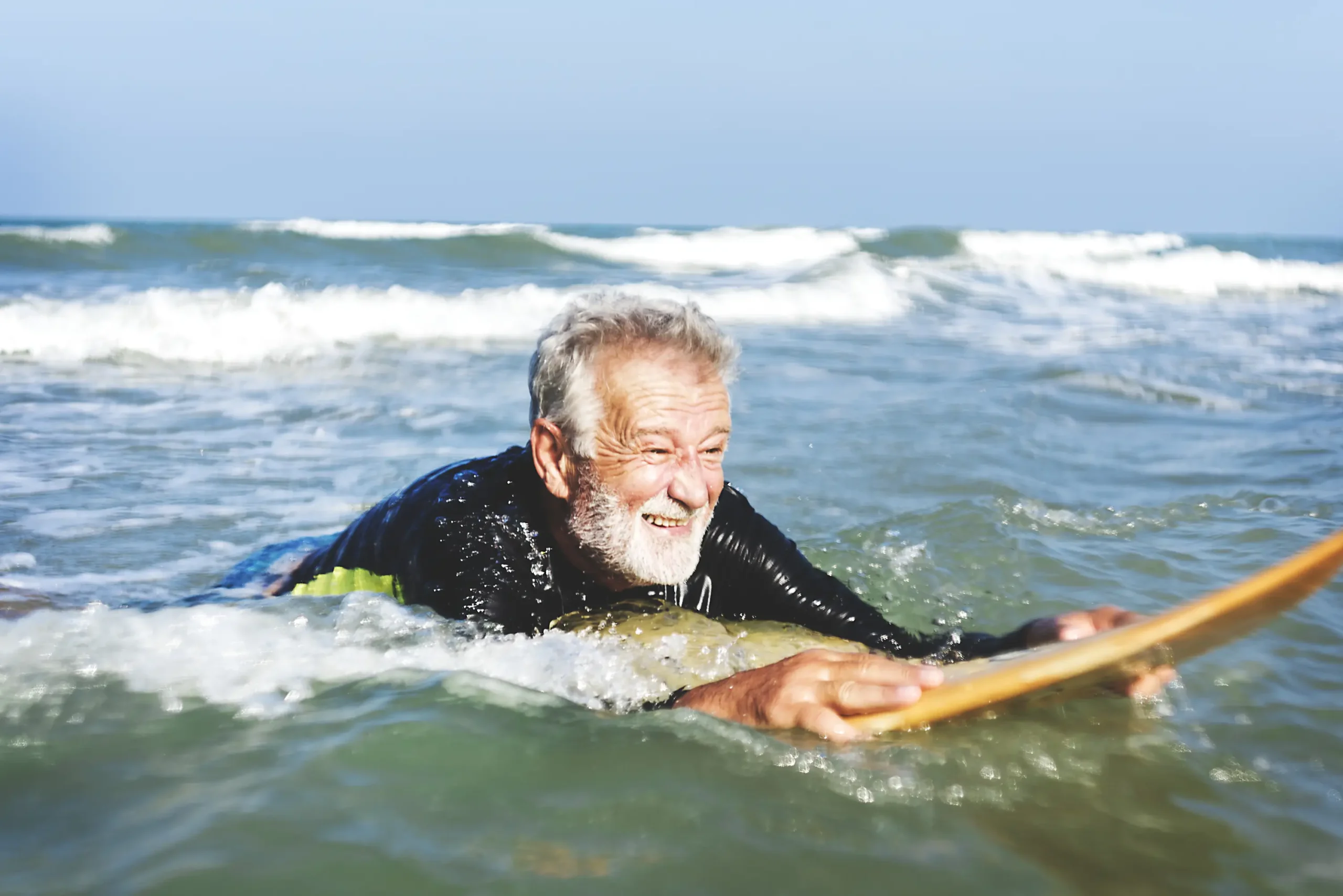 Un hombre mayor encima de una tabla de surf